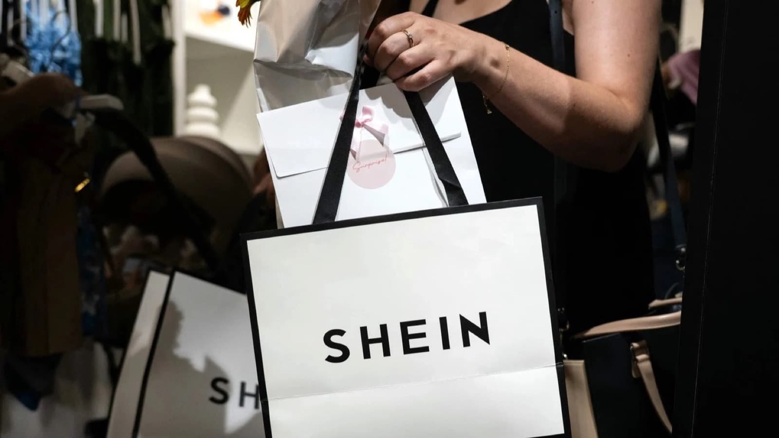 A shopper holding a white Shein shopping bag inside a clothing store