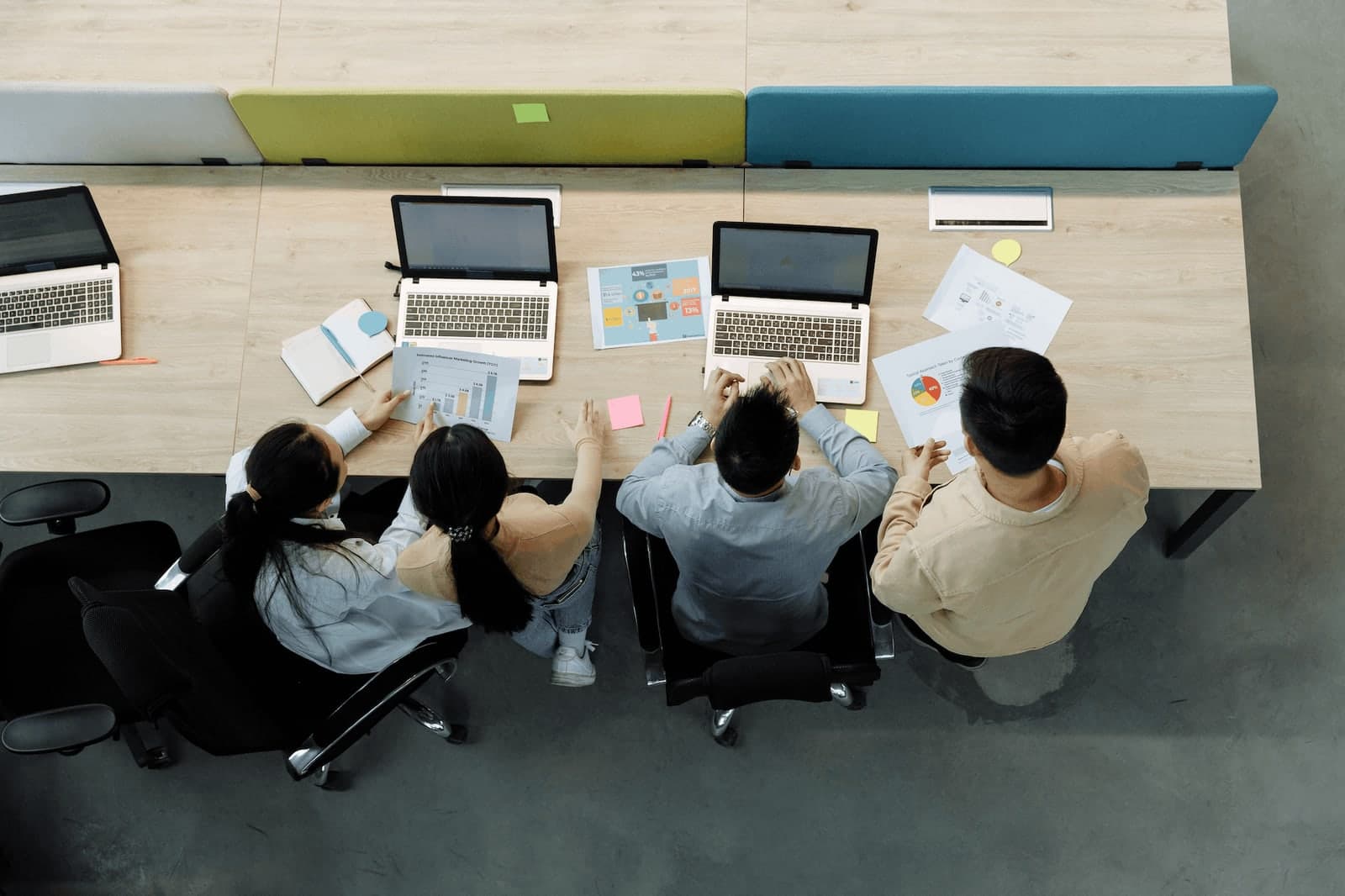 Overhead view of a marketing team reviewing analytics charts and laptops at a shared desk