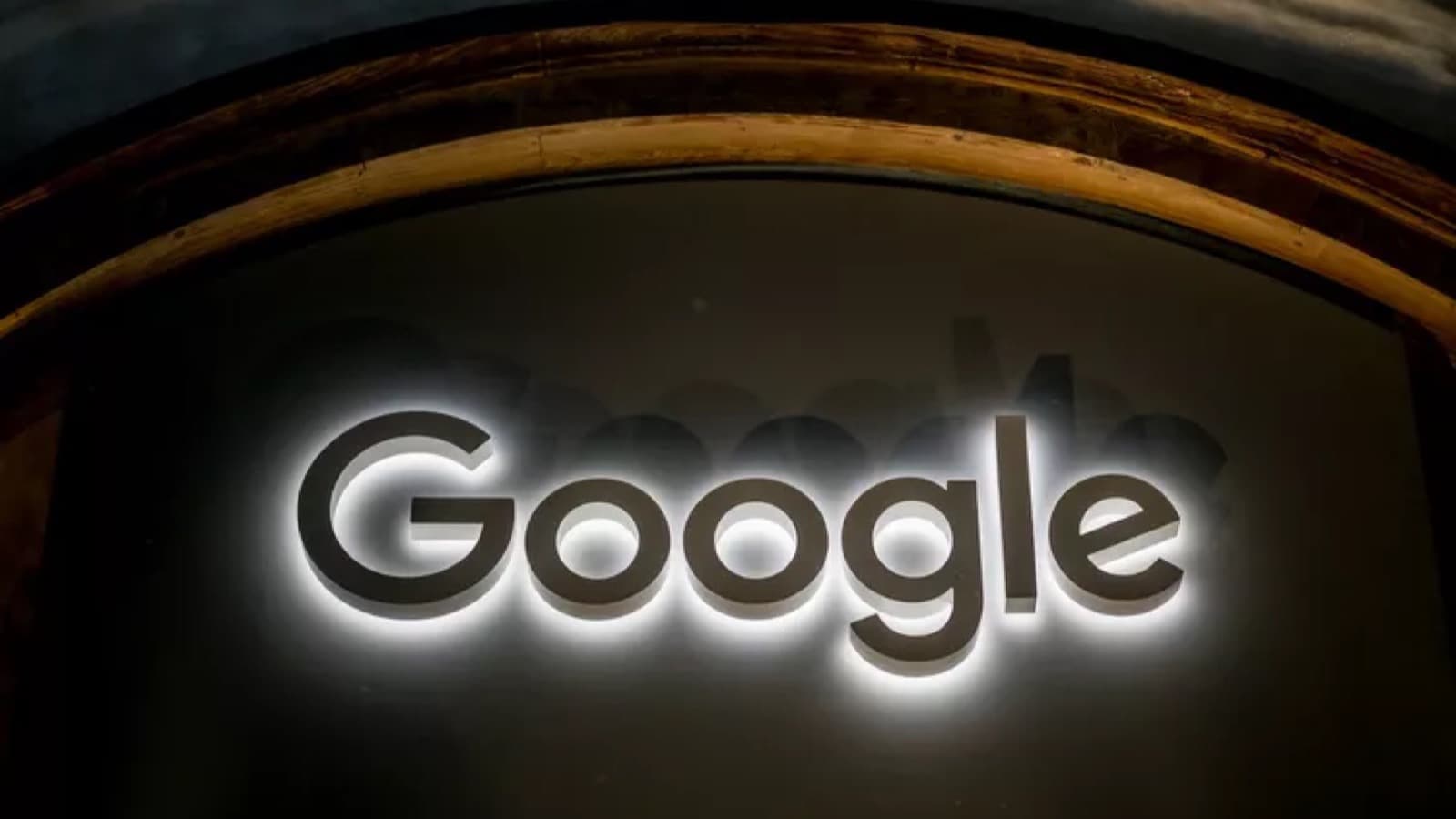 A glowing Google logo sign mounted on a dark curved wooden archway