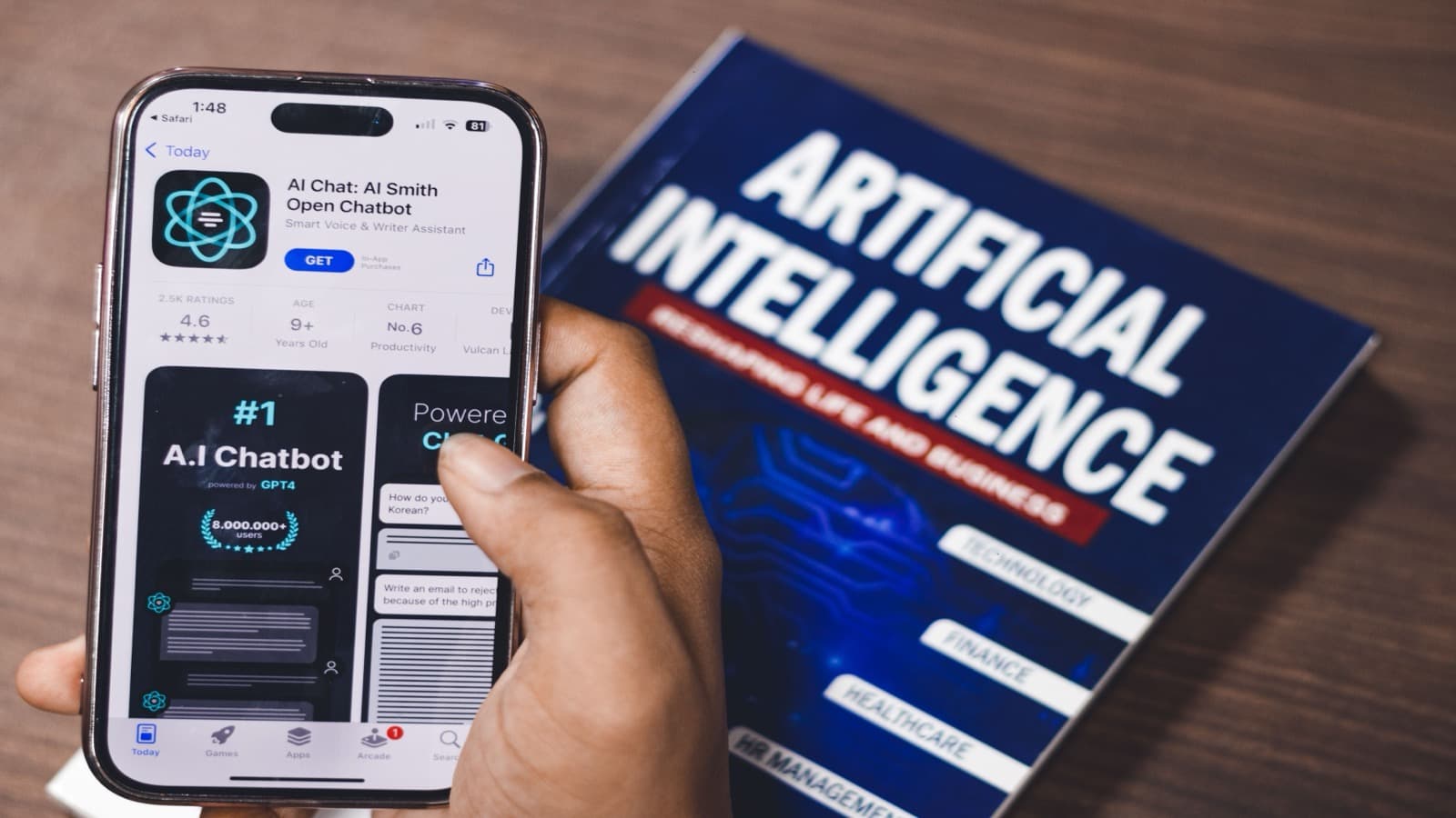A hand holding a phone showing an AI chatbot app beside a book titled Artificial Intelligence, illustrating the rise of AI tools in marketing
