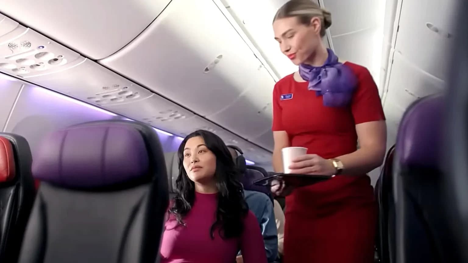 Virgin Australia cabin crew member serving a passenger on board a flight