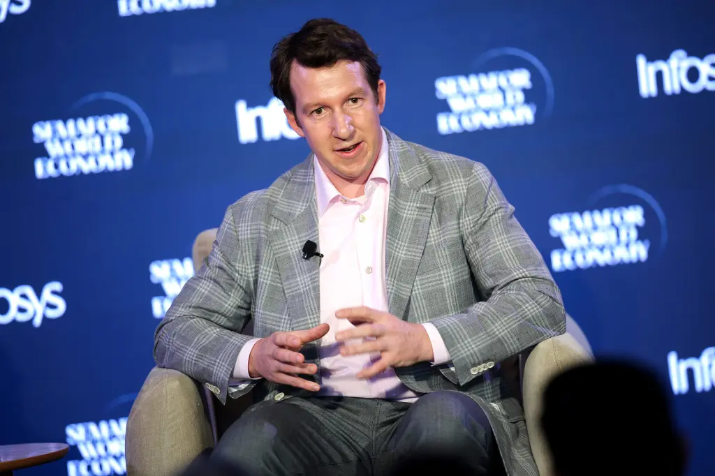 Jack Clark gesturing with both hands while seated on stage in front of a Semafor World Economy backdrop