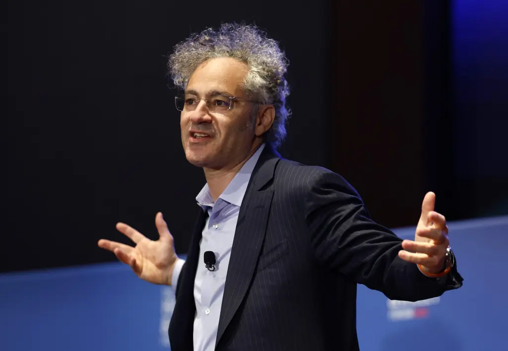 Alex Karp gesturing with both hands while speaking on stage