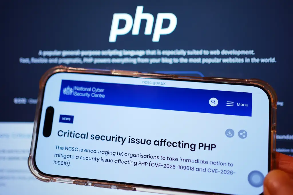 A phone displaying a UK National Cyber Security Centre alert about a critical PHP vulnerability