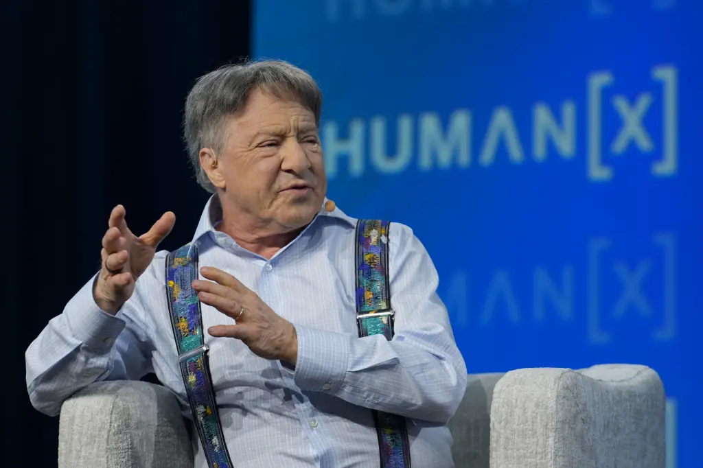Ray Kurzweil gesturing while speaking on stage in front of a HumanX conference backdrop