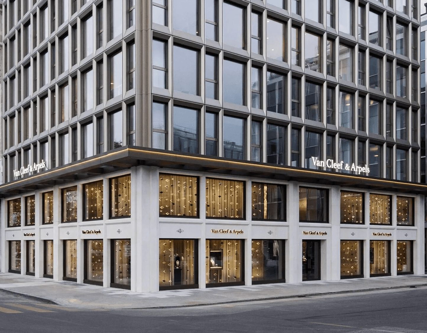 The Van Cleef and Arpels flagship boutique on a Geneva street corner with lit window displays at dusk